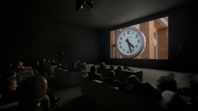 An audience takes in a scene from Christian Marclay's The Clock
