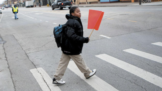 A neighborhood student uses the newly installed crossing flags at the intersection of 63rd and Talman to cross the street on Chicago's south side on Thursday, December 15, 2011.