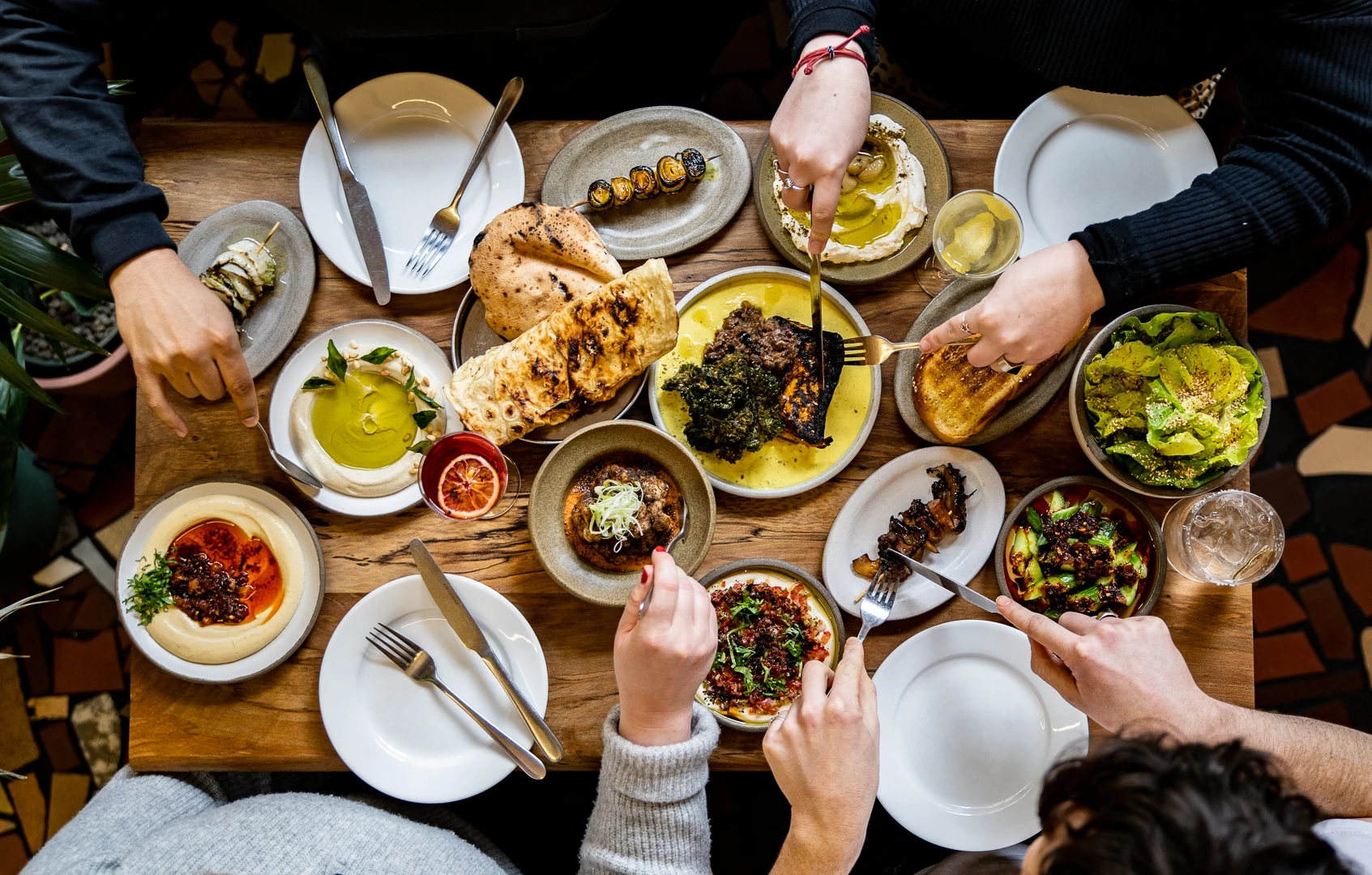 Hands reaching to grab a forkful of food from Bubala's vegetarian sharing plates