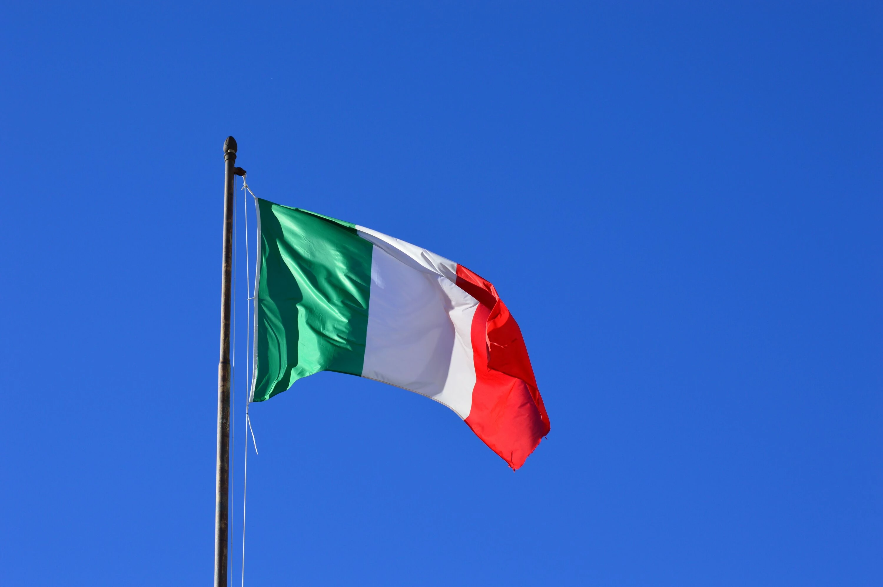 Italian flag flying against a vibrant blue sky, symbolising national pride and identity