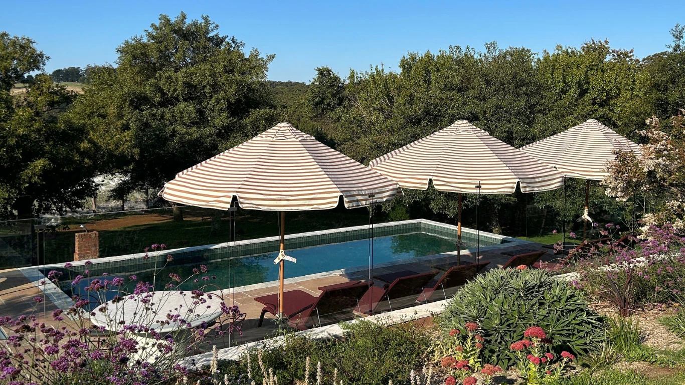 A pool with umbrellas at Dairy Flat Farm and Lodge.