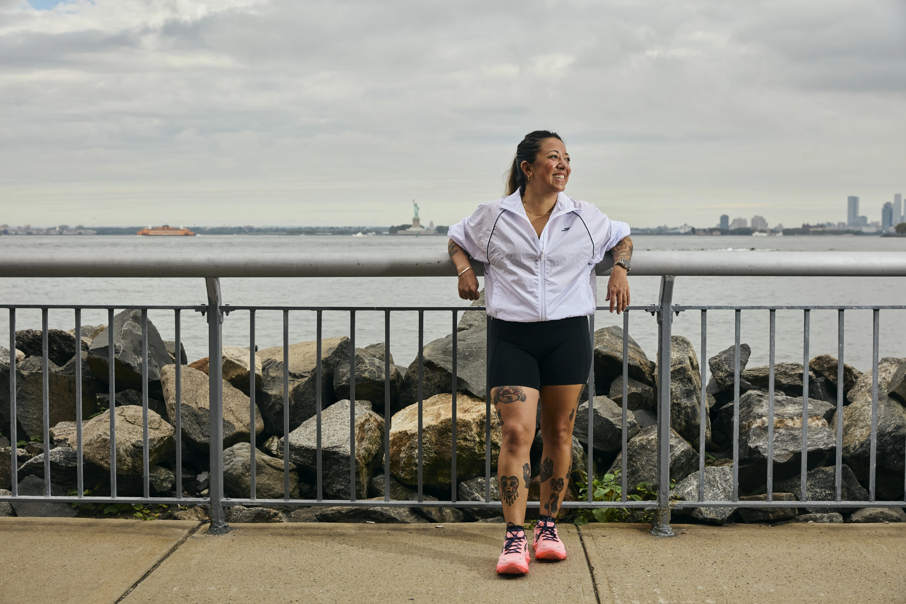 Ayaka Guido leaning against a fence Red Hook with the Statue of Liberty behind her