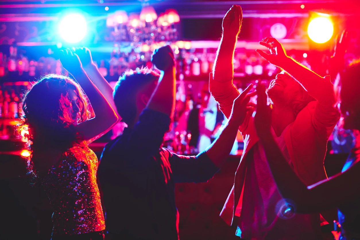 Group of dance lovers enjoying disco in nightclub