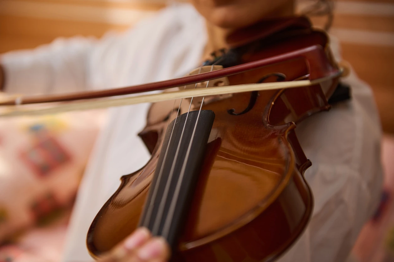 A close-up view of a musician gracefully playing the violin. The image captures the intricate details of the violin strings and bow, highlighting the skill and passion involved in playing music.