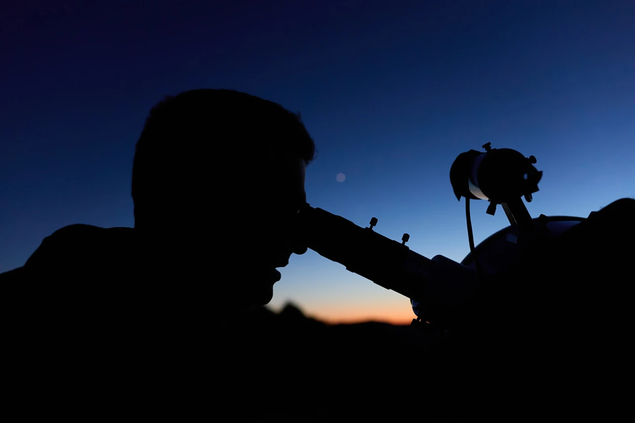 Amateur astronomer observing stars, planets, Moon and other celestial objects with a telescope in nature.