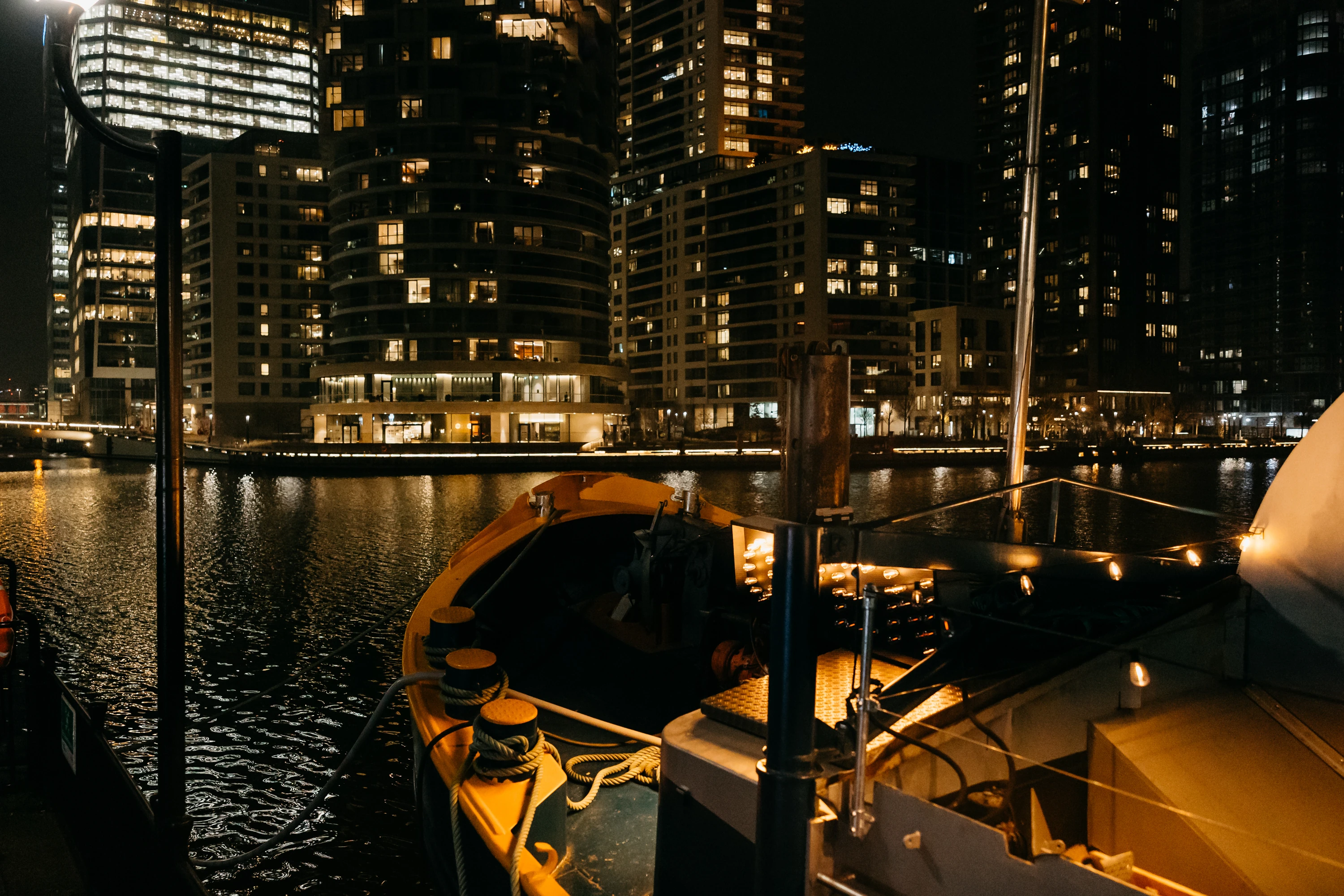 The bow of Theatreship with views of Canary Wharf at night