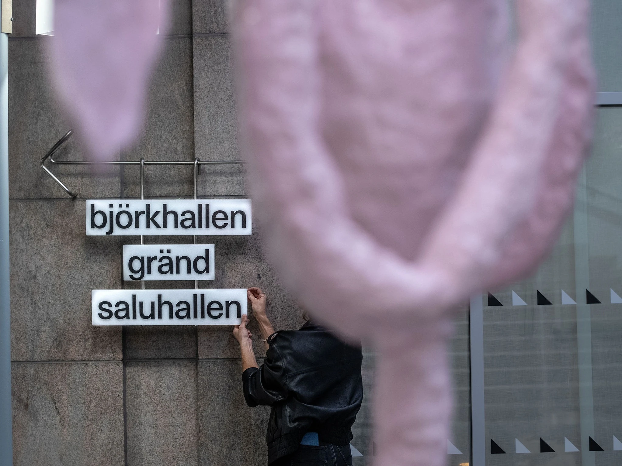 The entrance to S&ouml;derhallarna at night: a red neon sign above a curved, red-lit doorway covered in posters announcing the reopening on 23 October.