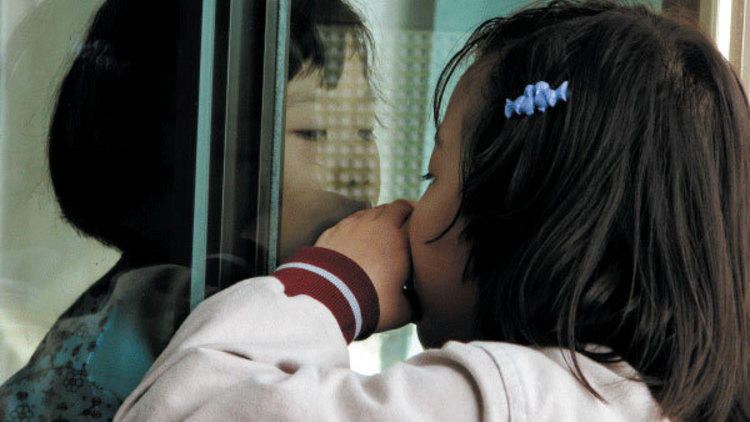 NO PANE, NO GAIN Kim Song-hee, left, peers through the window at her big sister.