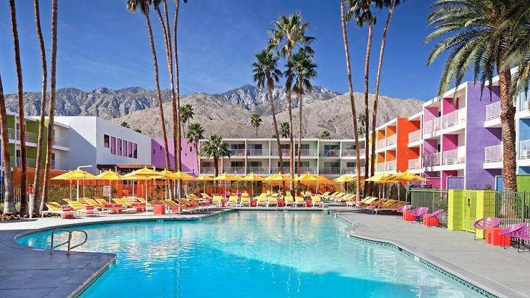 The Saguaro Palm Springs outdoor pool with colourful buildings and palm trees