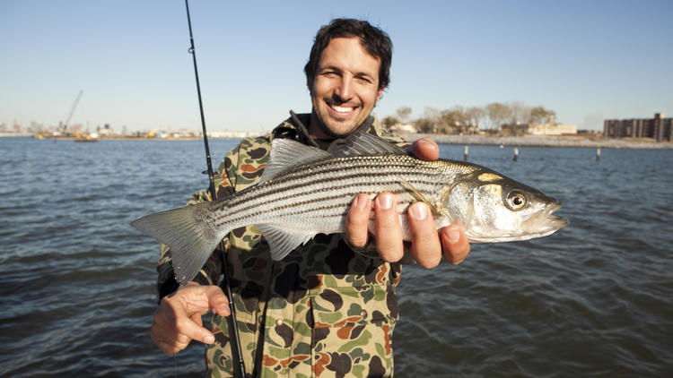 Ben Sargent with a small striped bass off the coast of Red Hook,