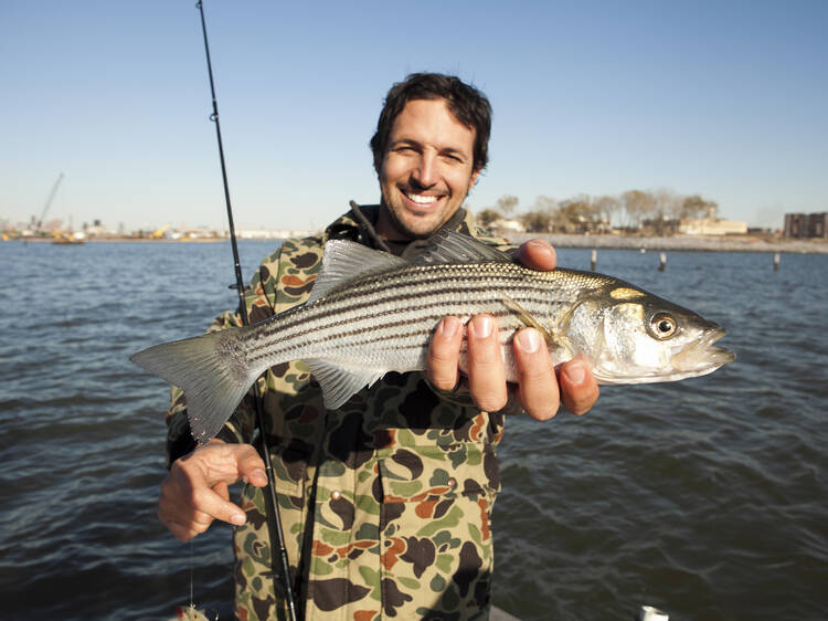 Ben Sargent with a small striped bass off the coast of Red Hook,