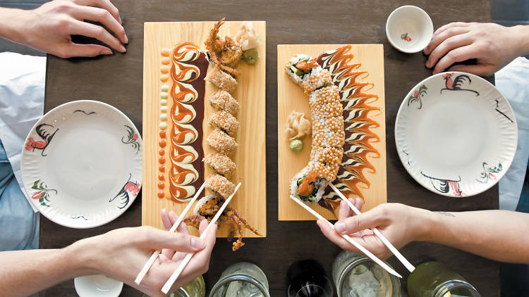 two people eating sushi rolls