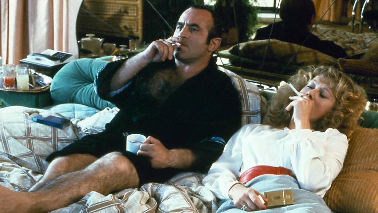 A still from the film The Long Good Friday of a man and woman smoking on a bed