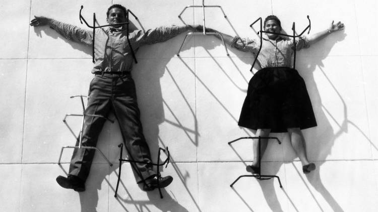 Charles and Ray Eames posing with chair bases. © Eames Office LLC