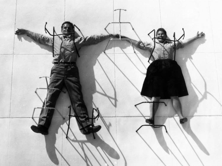 Charles and Ray Eames posing with chair bases. © Eames Office LLC