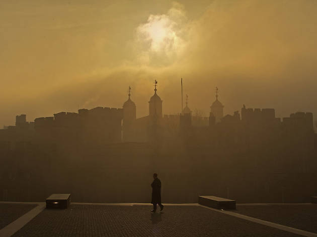 A lone figure patrols the Tower of London's moat during a hazy sunrise. A lone figure patrols the Tower of London's moat during a hazy sunrise.