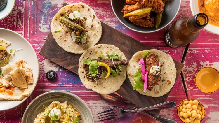 A top down shot of a collection of food dishes on a colourful pr