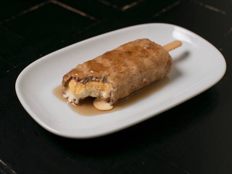 A close up shot of a deep fried golden gaytime icecream on a pla