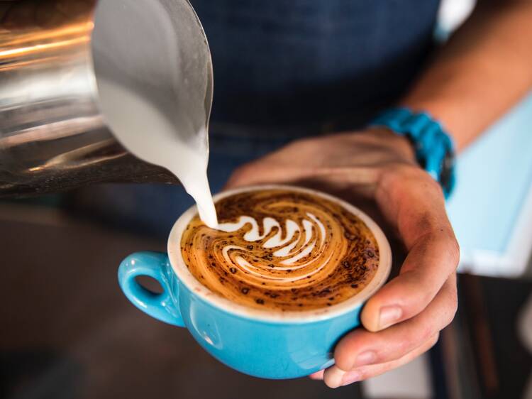 A barista pouring milk into