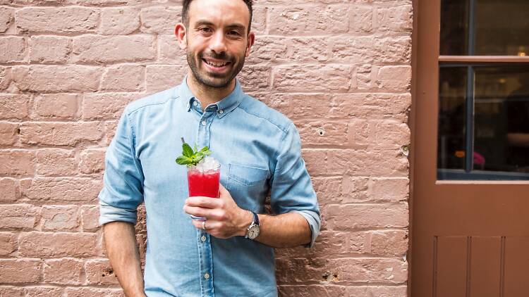 A shot of owner Tim Phillips against a brick wall holding a Red