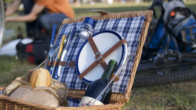 A generic shot of a picnic basket with plates, cutlery, bread an