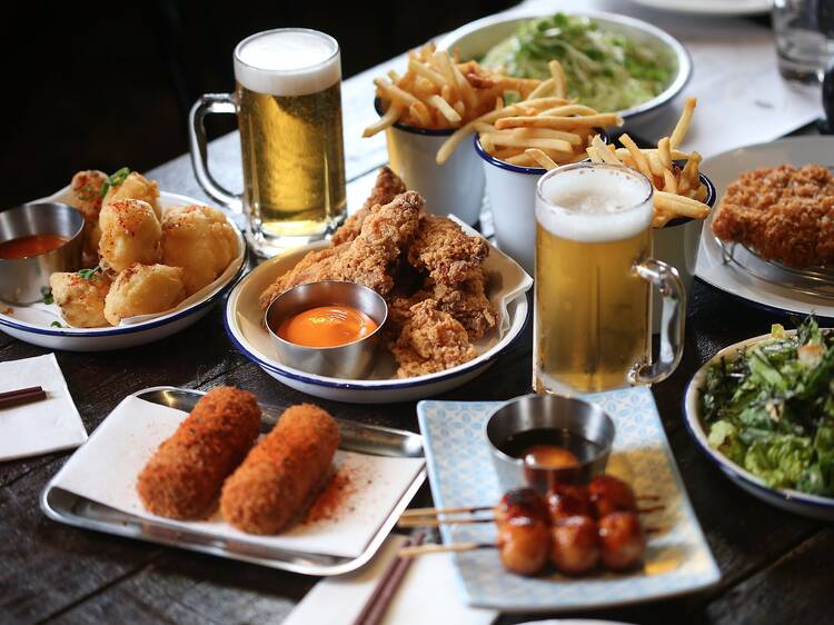 A shot of a table with various dishes of food and glasses of bee