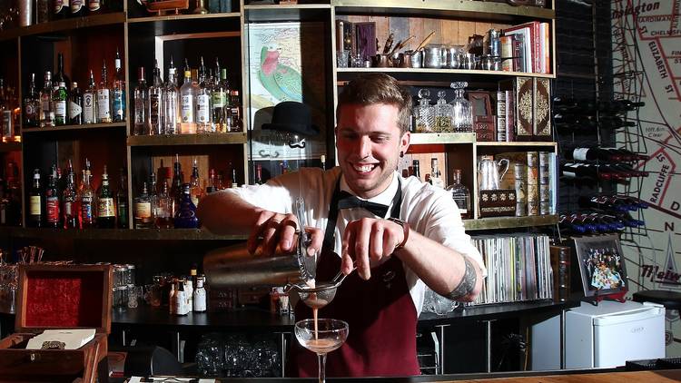 A bartender behind the bar at Mr Wow's Emporium pouring a cockta