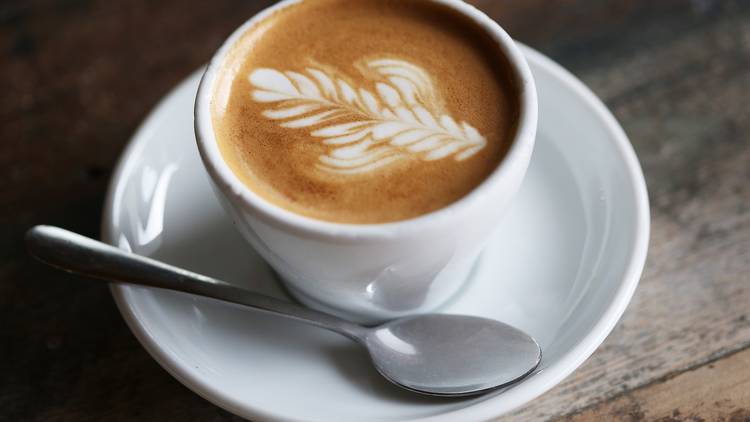 A close up shot of a coffee with latte art on a wooden table at