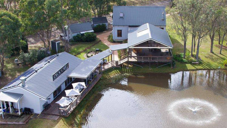 An aerial shot of two buildings and a pond that make up Deck Cafe