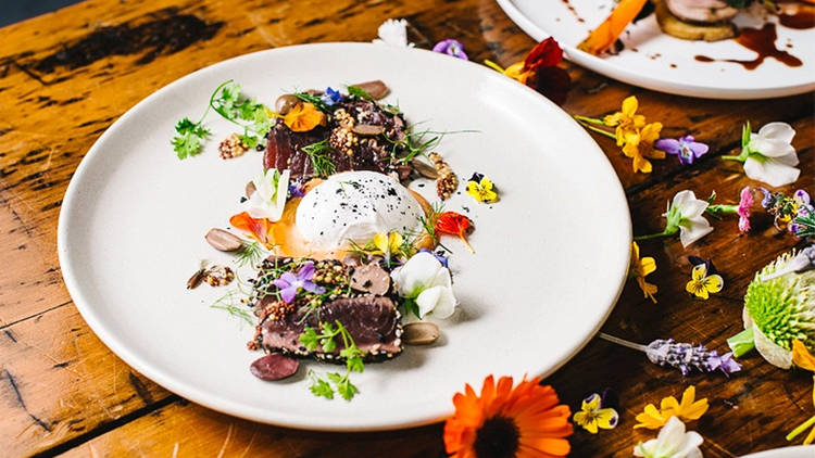 A shot of a poached egg with meat sprinkled with flowers at Circa 1876