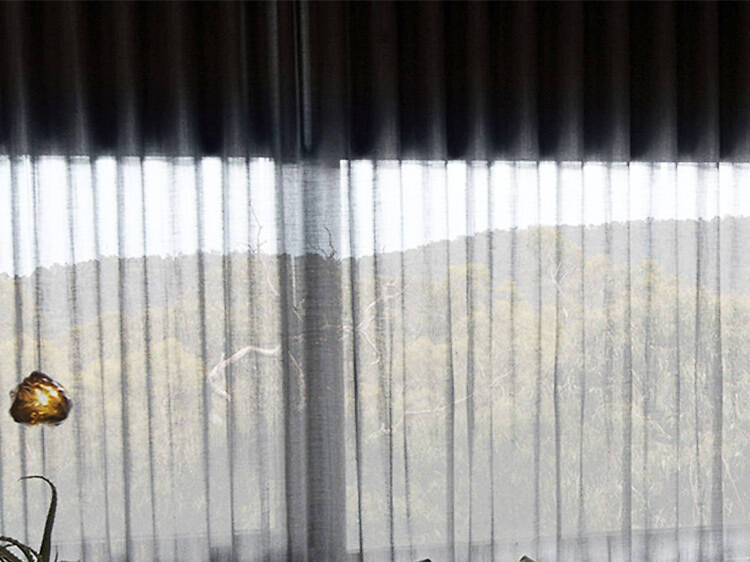 A shot of a guest room with a bed, couch and a large window overlooking trees and mountains