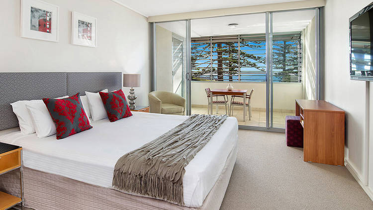 A shot of a guest room with a bed at The Observatory Hotel. The window overlooks the water