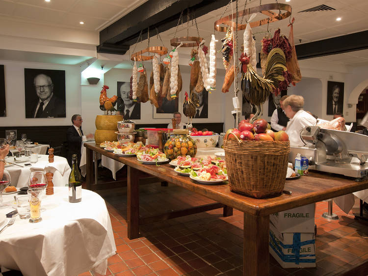 An interior shot at Machiavelli showing a centre table with various foods and hanging deli meats above it