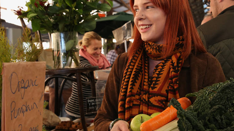 A woman holds a basket of fresh fruit and vegetables