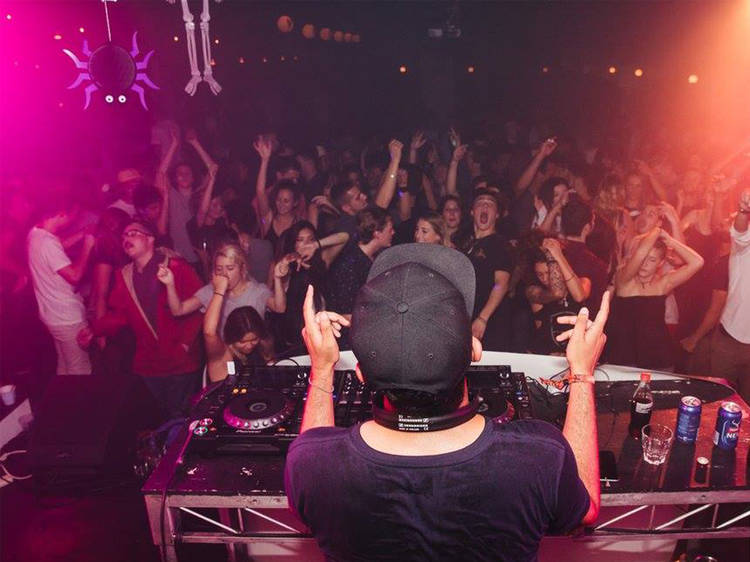 A shot of a DJ in front of a crowd of people dancing at Sosume