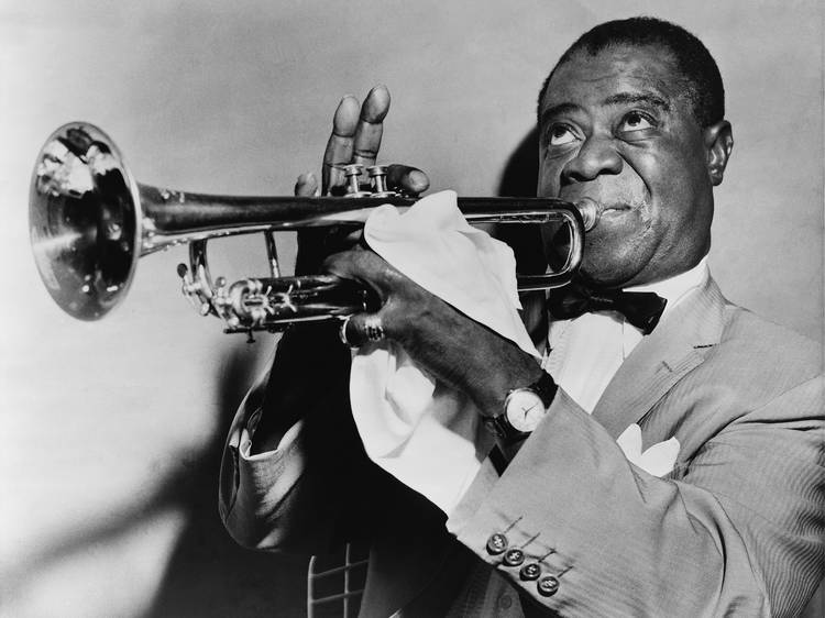 A black and white photograph of Louis Armstrong playing a trumpet