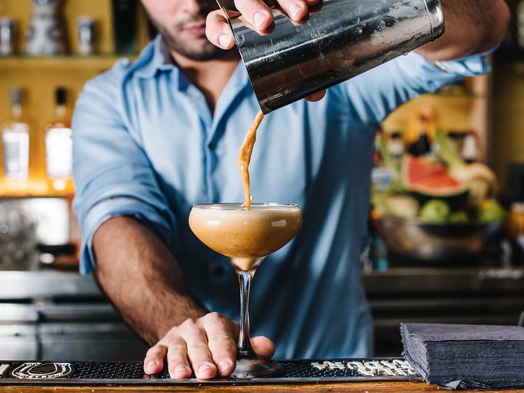 A bartender behind the bar at Barrio Cellar pouring an espresso martini