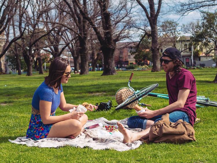 A couple sitting on grass having a picnic