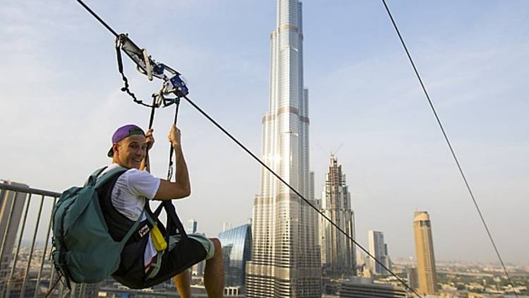 A man ziplines past the Burj Khalifa in Dubai