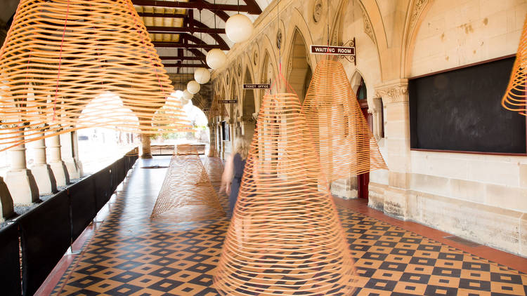 Image of the platform at Mortuary Station, with artist Charwei Tsai's spiraling cones of incense hanging from the ceiling at different depths.