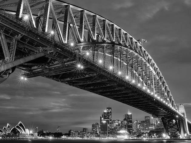 NOT FOR REUSE Australian Centre for Photography advertorial image A black and white photograph of the Sydney Harbour bridge, taken at night with the lights on.