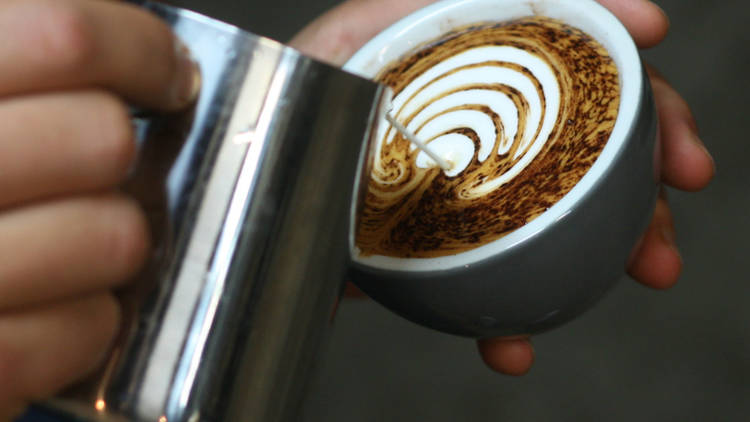 someone pouring foam over coffee