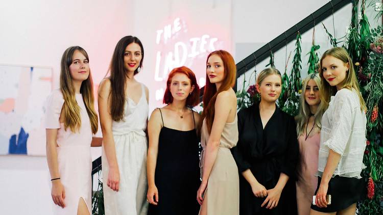 The Ladies of the Ladies Network Stand in front of a Pink Neon Sign 