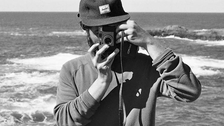 A man holds a camera over his face in a black and white photo