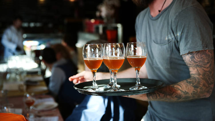 A bartender carrying a tray of beers during Good Beer Week