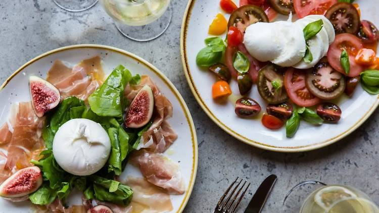 two plates with different dishes on them. With wine next to each plate