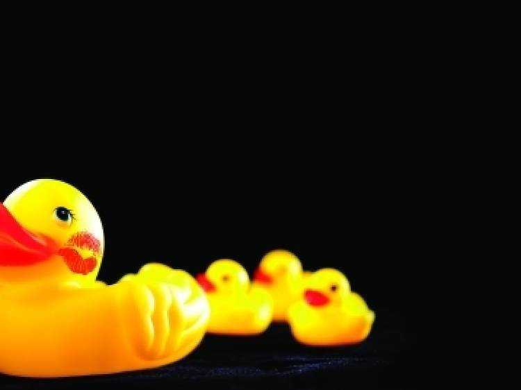 A row of rubber ducks, the front one has a lipstick stain