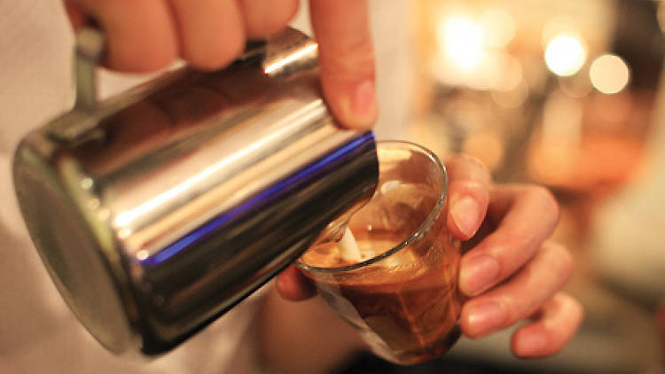 Shot of barista pour milk into coffee