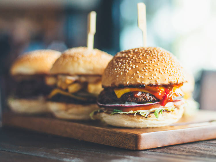 Three burgers on a wooden board