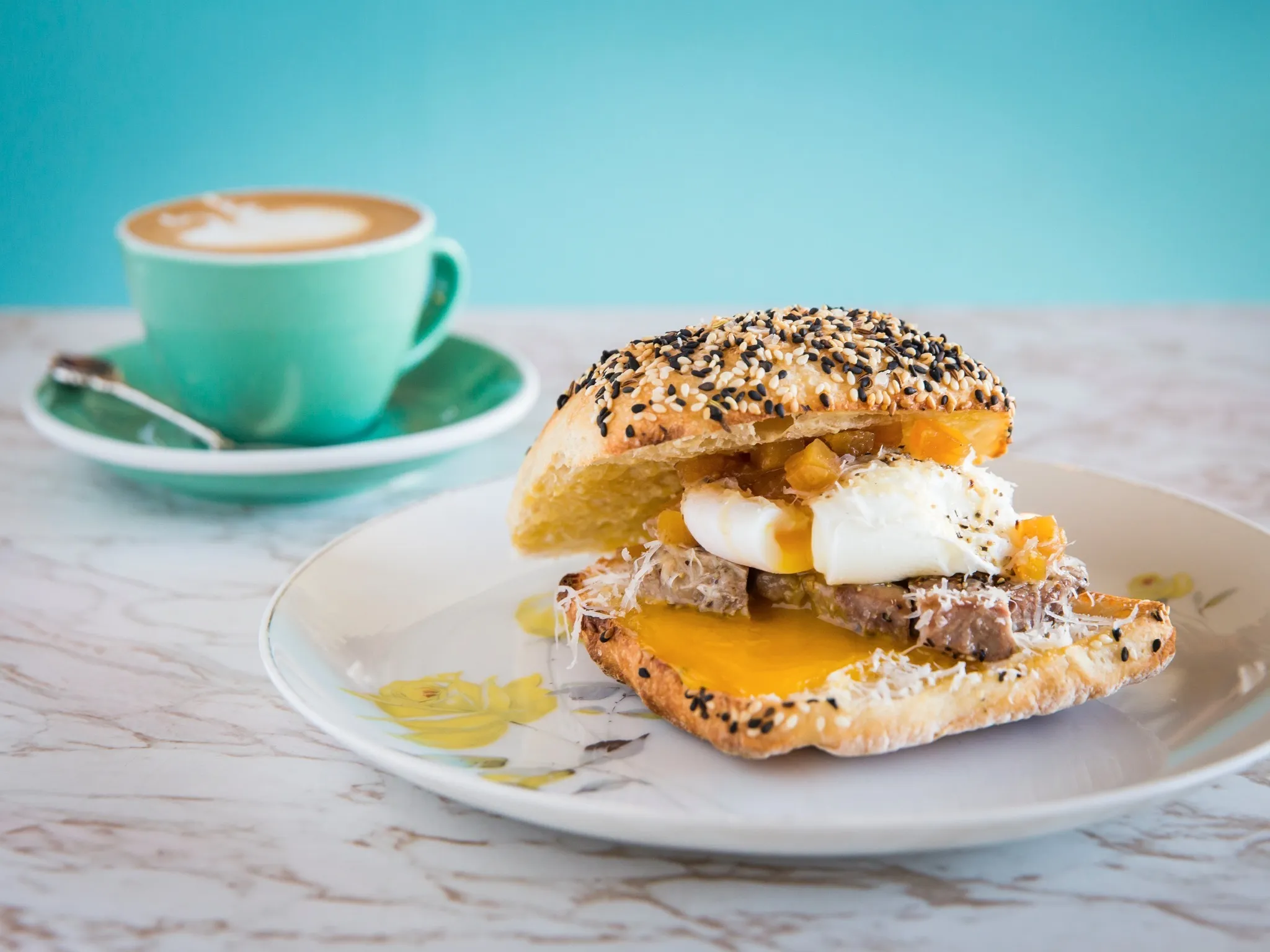 A bacon and pork roll with cup of coffee.